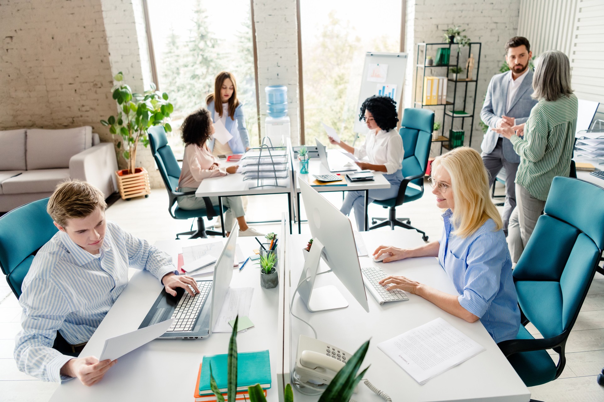 Modern office setting with diverse teamwork collaboration and professional interactions among colleagues in bright and stylish workspace